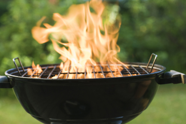 klotgrill med eldsflammor som står i en grön trädgård