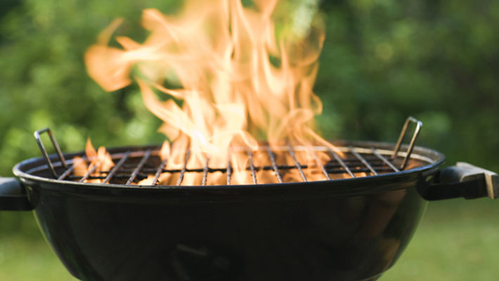 klotgrill med eldsflammor som står i en grön trädgård